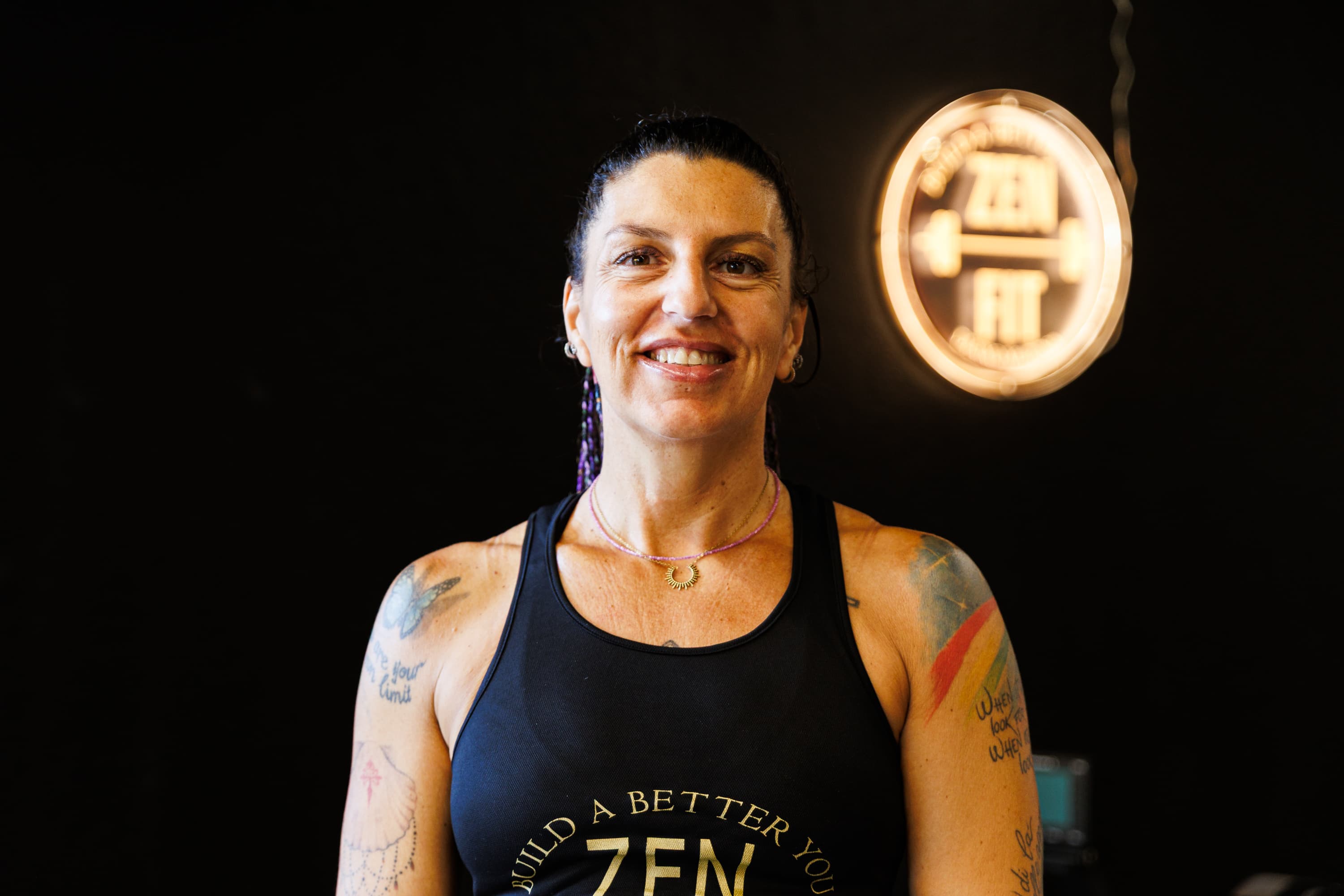 Paola Girardi in canotta Zenfit, davanti all'insegna luminosa della palestra.